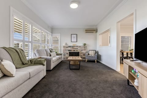 Light-filled living room with flat screen TV, seating area & split-system air-conditioner. 