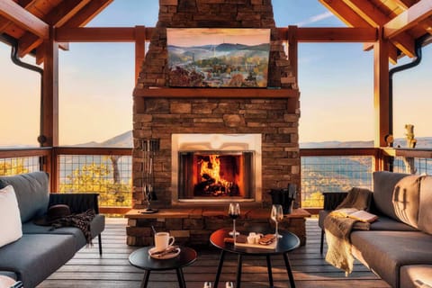 Cozy outdoor seating area with a stone fireplace and mountain views at sunset.