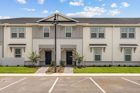 Step into a charming exterior featuring crisp white siding and modern accents that invite you to relax. The landscaped pathway, flanked by young trees, leads you to your doorway, setting a welcoming tone for your stay.