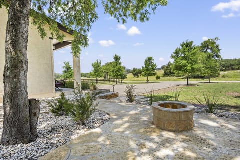 Step outside and unwind! Enjoy the serene outdoor space with a charming fire pit, lush greenery, and a peaceful view of the expansive property, perfect for relaxing evenings.