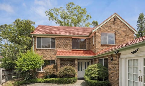 Front exterior of a two-storey brick home with landscaped garden and driveway.