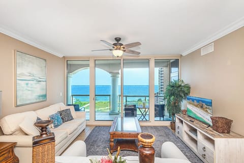 Step into your coastal retreat where floor-to-ceiling windows frame endless water views. Relax in the bright living space with plush seating and your own private balcony just beyond the glass doors.