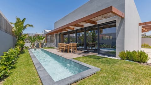 Outdoor deck beside a sleek pool, ideal for relaxing or dining al fresco in a private garden setting. #PT #Portugal #Ericeira #PoolsideVibes #OutdoorDining #TranquilGetaway