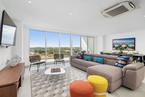 Your spacious living room awaits with a cozy sectional, vibrant pops of color, and sweeping views that invite you to unwind in style.
