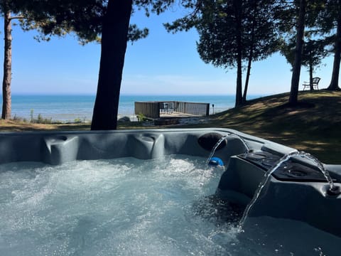 Lakeside hot tub set among trees, ideal for unwinding outdoors in any season.