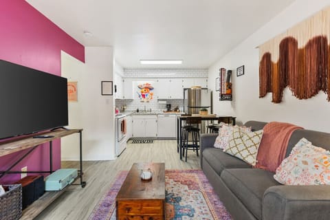 Comfortable Queen sleeper sofa in the living room with a Smart TV, fun decor, and easy access to the kitchen and dining areas.