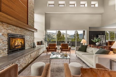 Stunning and spacious living area featuring soaring ceilings, breathtaking views, abundant natural light, and a cozy fireplace
