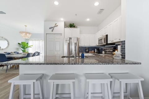 Bright and stylish kitchen with granite countertops, modern appliances, and a breakfast bar with seating for four. Perfect for casual meals or chatting while cooking, this space blends coastal charm with everyday convenience.