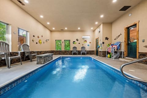 Soak up the cabin vibes while enjoying the water—this spacious pool room brings the outdoors in with large windows and colorful aquatic decor.