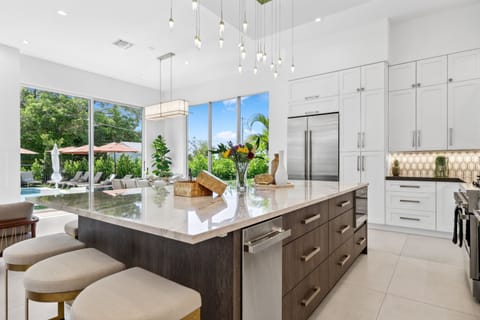 Bright and modern chef’s kitchen with marble island and pool views—your Delray Beach stay, elevated.