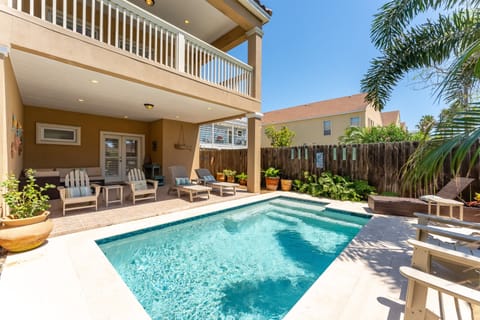 Relax in your private backyard oasis featuring a sparkling pool, covered patio, and outdoor loungers