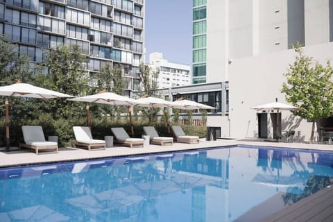 Take a refreshing dip in the shared outdoor pool surrounded by sleek loungers & modern buildings
