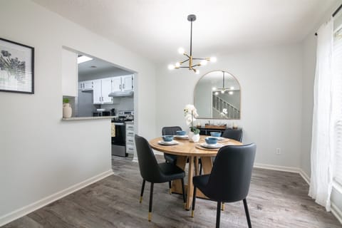 A cozy dining space seamlessly connected to the kitchen, featuring a stylish black-and-gold chandelier above a round dining table.