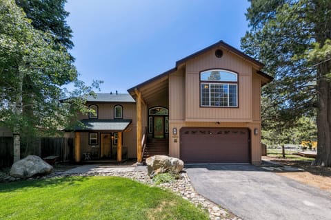 A mountain retreat with warm wood siding nestled among towering trees, featuring a welcoming front entrance and peaceful forest setting.