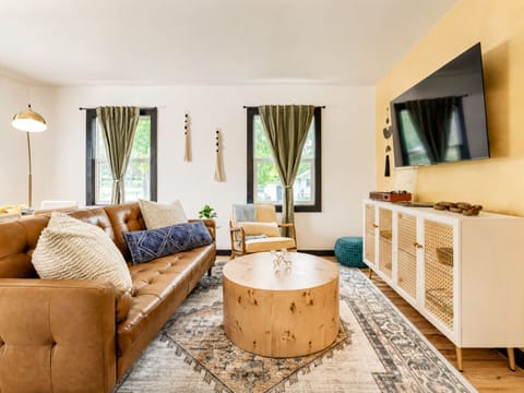 Bright, cozy living room with leather sofa, natural light, and smart TV