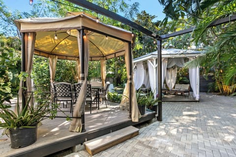 tropical oasis that has a BBQ area, hot tub, lounge seating, dining. and firepit