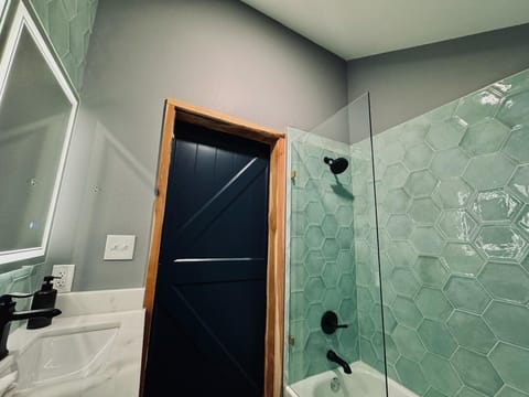 Beautiful shower/tub combo with half glass door and gorgeous light green tile
