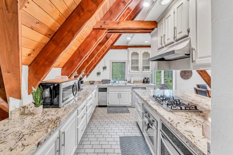 Kitchen: Stainless steel appliances, bar seating, tableware, cookware, gas range 