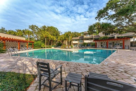 The community pool area offers a refreshing coastal retreat surrounded by lush landscaping and swaying palms.