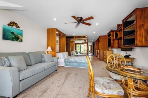 Relax in your open-concept retreat, where tropical charm meets comfort. A plush sofa invites you to unwind while the ceiling fan keeps things cool and breezy.