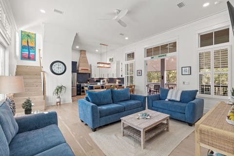 Sink into plush blue sofas in your open-concept living space, where coastal charm meets modern comfort with soaring ceilings and natural light.