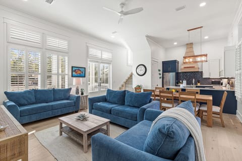 Sink into plush blue sofas in your bright, open living space where natural light flows through plantation shutters.