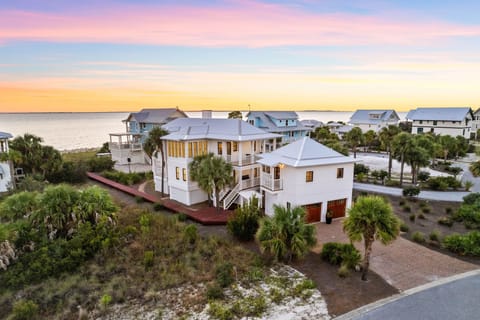 Stunning coastal home nestled among palm trees with spectacular sunset views over pristine waters and neighboring beach community.