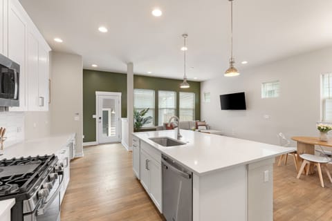 Open bright space with kitchen island, stainless steel appliances, and dining.