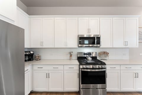 Modern bright kitchen with stainless steel appliances and ample storage space.