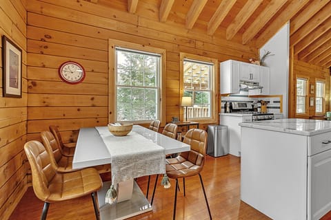 - Share meals at the dining table with woodsy charm   - Sunlight streams through large cabin windows   - Enjoy forest views while dining with friends