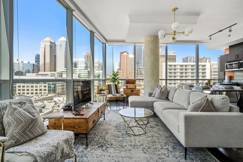 Living room with a 55` Smart TV, PS4, a record player and floor-to-ceiling, NW-facing windows with views of the Calgary tower & city skyline.