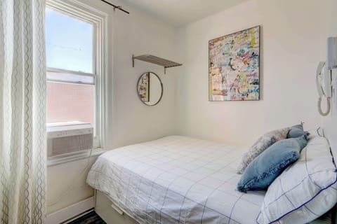 Bright room featuring a comfy bed, AC unit for ultimate comfort, and stylish artwork. 