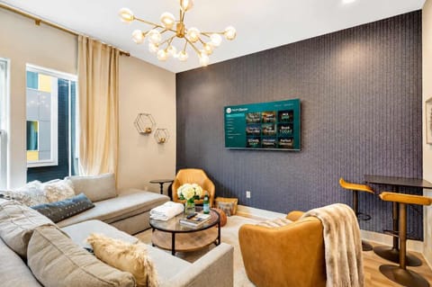 High ceilings with a modern chandelier, a sectional and two armchairs pointed at the TV, tall windows with soft drapes: this living room fits a group without feeling cramped
