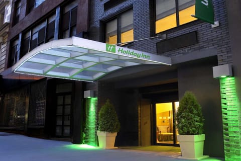Entrance with Holiday Inn canopy lit in green and large planters