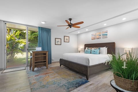 Unwind in this bright, coastal-inspired bedroom with a plush bed, gentle ceiling fan, and sliding door leading to your private garden oasis.