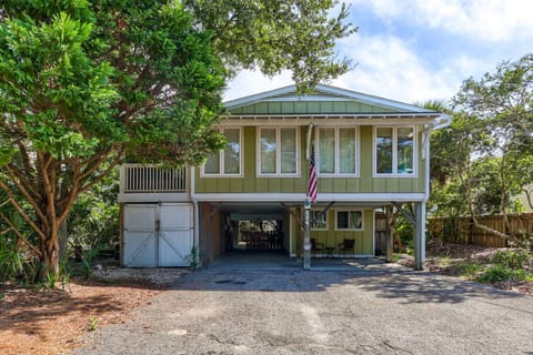 Charming coastal home elevated on stilts, surrounded by lush tropical vegetation and offering covered parking beneath.