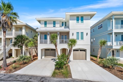 Modern coastal architecture welcomes guests to this pristine beach community property, featuring tropical landscaping and convenient parking.