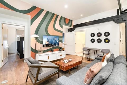 Unit 2: Living room with open-concept design featuring a white brick wall, Smart TV, and comfy sleeper sofa.