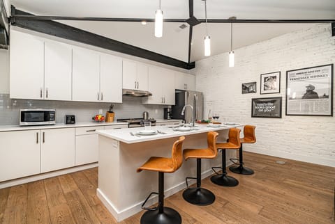 Unit 4: Kitchen with stainless steel appliances, white cabinetry and countertops, and kitchen island with bar seating for 4 guests. (5th Floor)