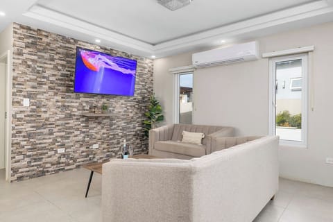 Relax in this cozy, modern lounge featuring a smart TV, and comfy L-shaped sofa. Natural light fills the room through large windows, while the air conditioning keeps things cool. Perfect for unwinding after a day of exploring!