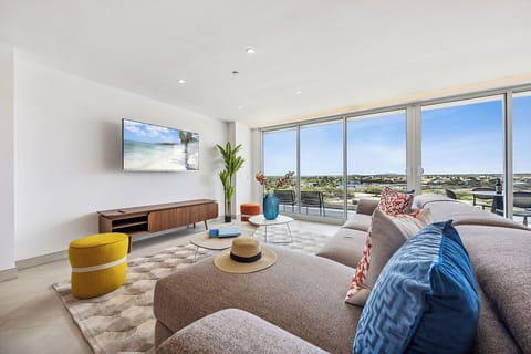 Relax in your bright, modern living room with stunning floor-to-ceiling windows framing expansive neighborhood views. Sink into plush seating, enjoy your smart TV, and step out to the terrace whenever you need fresh air.