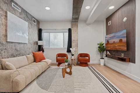 Kick back in a stylish living room featuring a large TV, lush plant accents, and soft lighting.