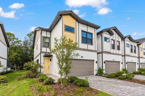 Step outside to appreciate the modern façade of this vacation home, where bright white and warm wood merge beautifully. The lush landscaping and vibrant greenery enhance the welcoming atmosphere, ensuring you feel right at home.