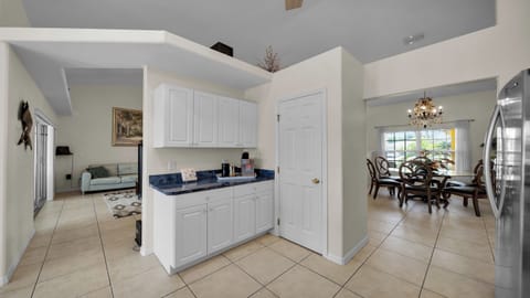 Open floor plan with convenient coffee station, view of the bright dining area with chandelier, and connection to the living room.