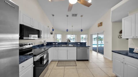 Open kitchen with island, spacious sink area, and wide view of the terrace, breakfast nook, and water – bright and functional.