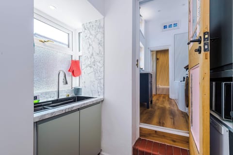 This sleek grey kitchen, featuring a stained glass door and access to the yard, is fully equipped with everything you need to cook comfortably away from home. A stylish and practical space for enjoying home-cooked meals during your stay.