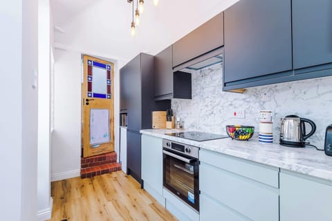 This sleek grey kitchen, featuring a stained glass door and access to the yard, is fully equipped with everything you need to cook comfortably away from home. A stylish and practical space for enjoying home-cooked meals during your stay.