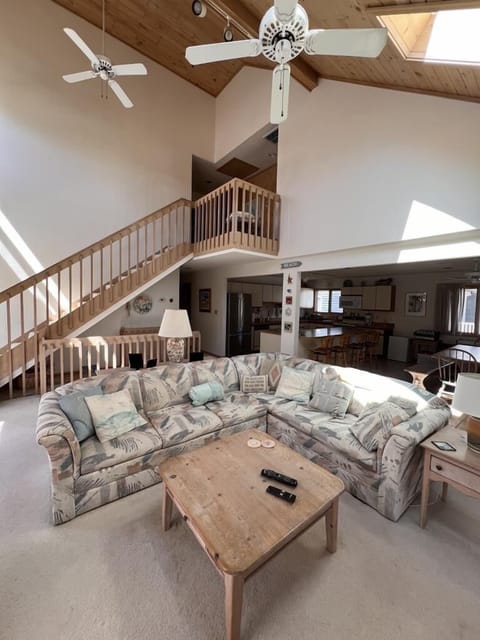 An airy open-concept living space showcasing a cozy sofa arrangement and a staircase leading to an upper level.