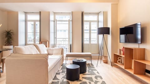Stylish and sun-filled living room with floor-to-ceiling windows, modern décor, and a cozy vibe—perfect for relaxing after a day in the city. #DesignApartment #LisbonStay #NaturalLight #LovelyStay