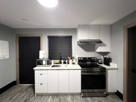 This photo showcases the functional side of the kitchen area, featuring a stacked washer and dryer unit next to the dining table. The kitchen counter with a sink and the entrance to another room are also visible, emphasizing the space's convenience.